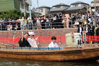 嫁入り舟で遊覧しながら来場者から祝福を受ける田中さん夫妻