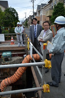 舞浜で下水道復旧状況を市職員から聞く谷副大臣（右から２人目）
