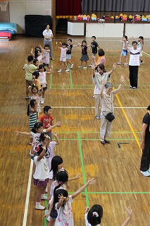 自治会員（右側）を手本に盆踊りを練習する児童