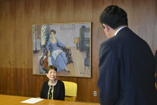 『レッスン』をバックに松崎市長の感謝の言葉を受ける久代さん