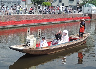来場者から祝福を受けながら嫁入り舟で遊覧する亀山さん夫妻