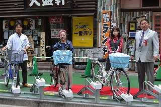  松本会長（右）とラックに自転車を駐車する同協議会の関係者